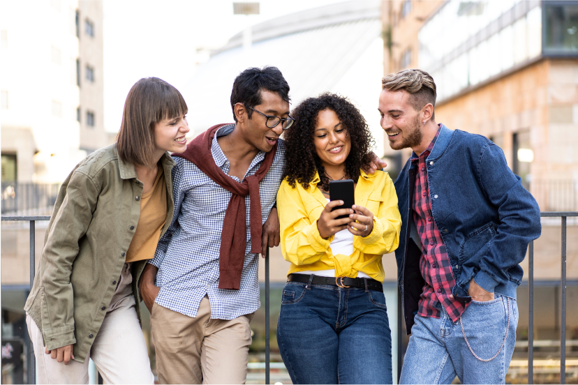 Group of people standing together looking at a mobile phone held by one of the people