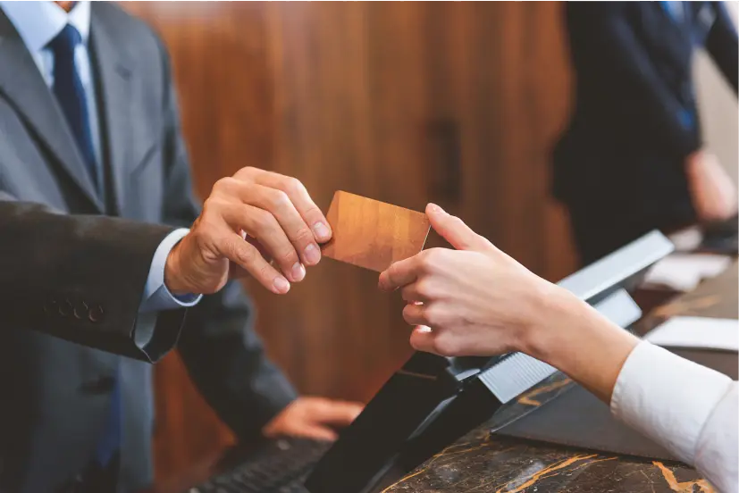 Close up photo of a hotel employee handing a keycard to a guest