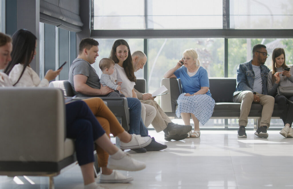 Diverse patients in waiting room some on devices