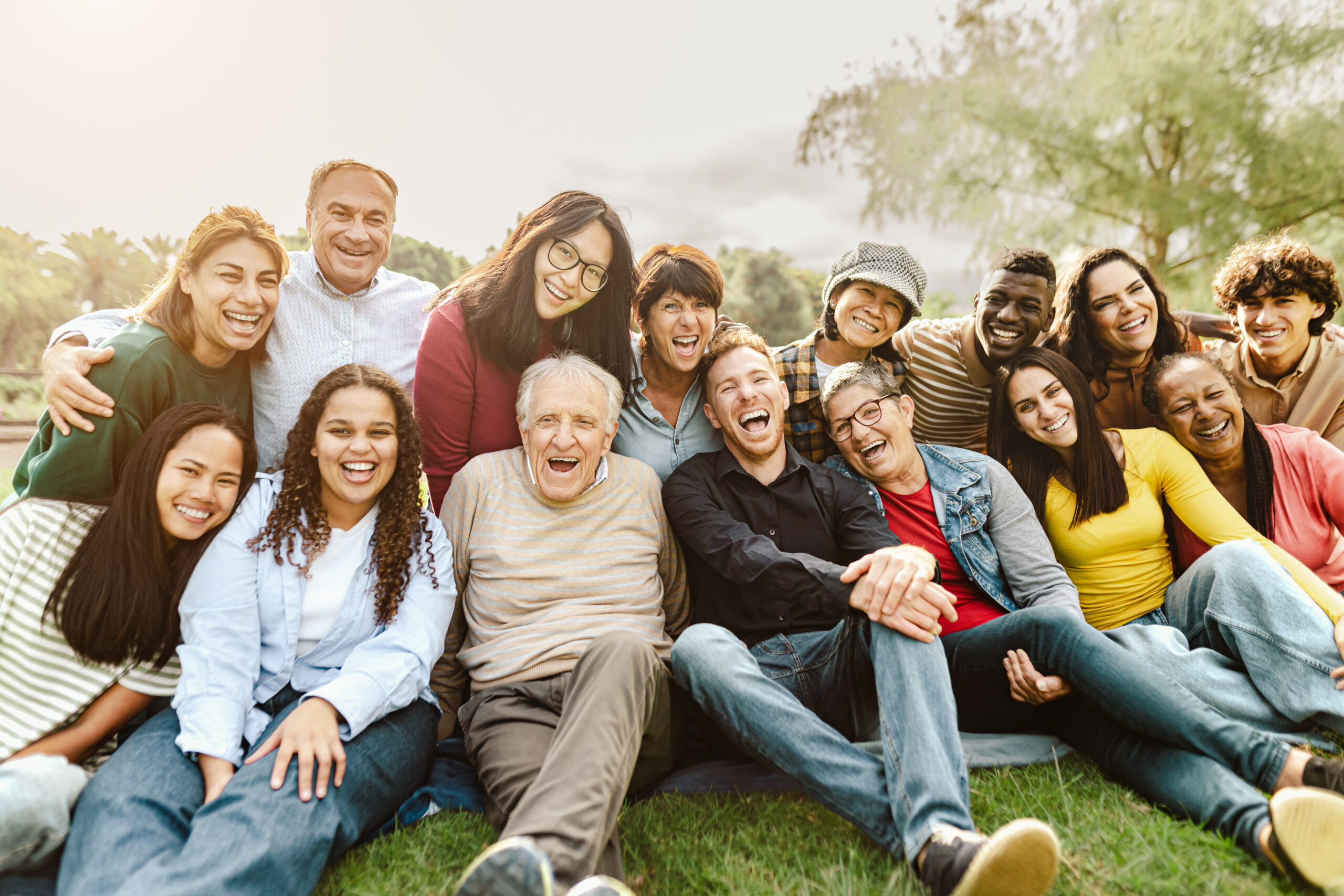 Leadspace A group of people of all demographics sitting on the grass, laughing and smiling.